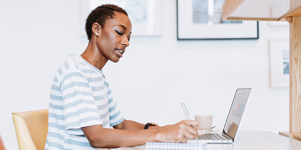 Person writing at a desk on a laptop