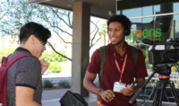 Black male journalism workshop header image. Two men speaking to eachother and smiling