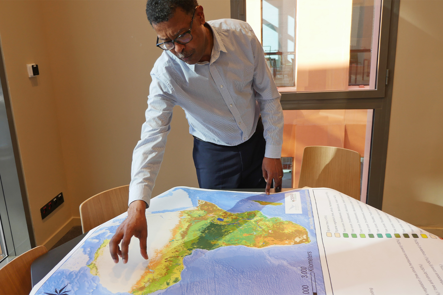 Soil scientist Fassil Kebede leaning over map of soil in Africa.